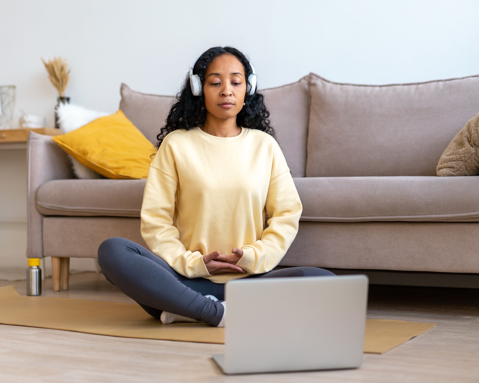 African-american female participating in virtual Breathwork Class at home to practice breathing techniques
