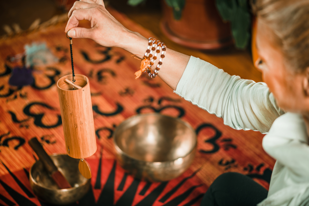 Woman uses chime during Elemental Sound Bath to foster the sense of air movement